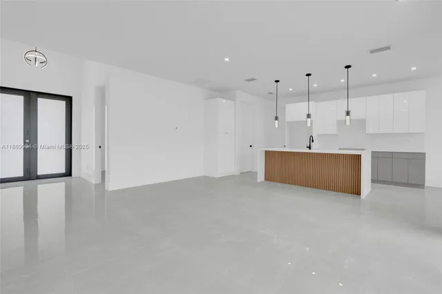 a view of an empty room with kitchen view and a window