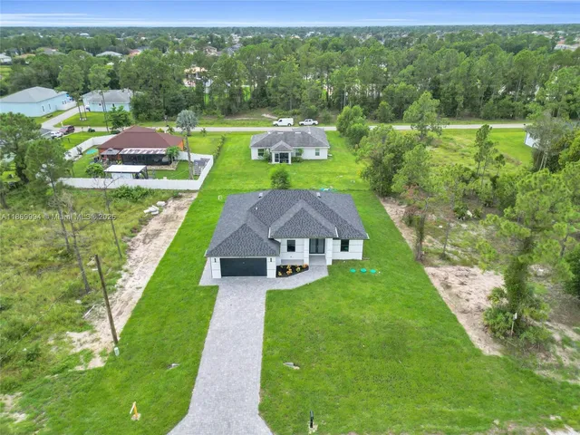 a aerial view of a house with swimming pool big yard and large trees