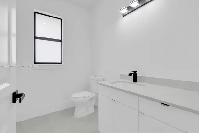 a bathroom with a granite countertop sink toilet and a mirror