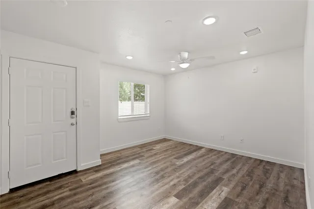 an empty room with wooden floor and windows
