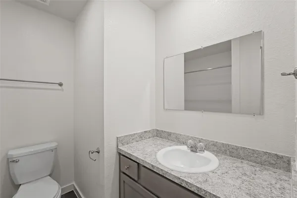 a bathroom with a granite countertop sink toilet and a mirror