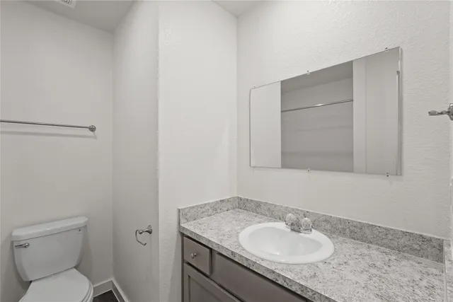 a bathroom with a granite countertop sink toilet and a mirror