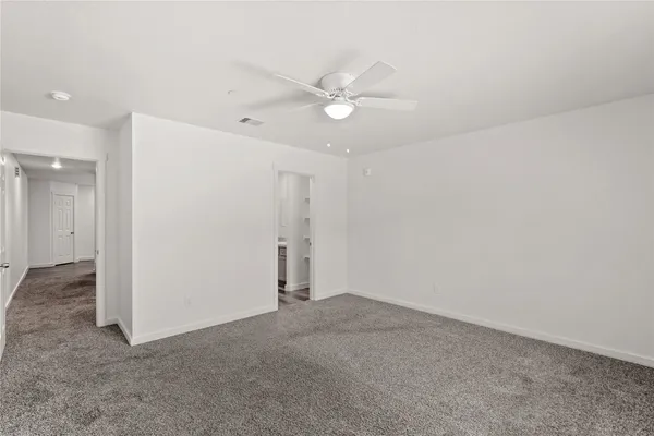 an empty room with a ceiling fan and a bathroom
