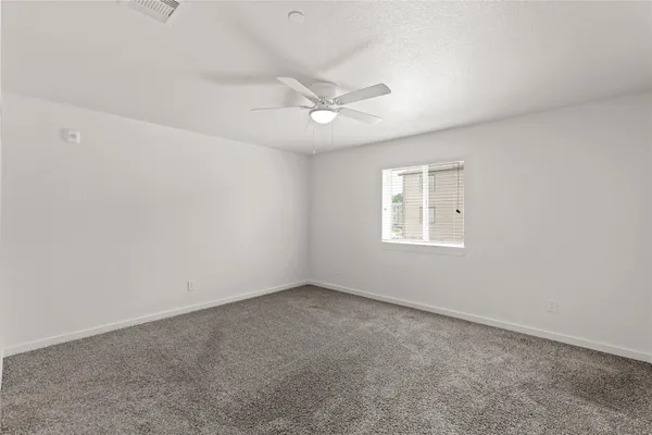 an empty room with a window and ceiling fan