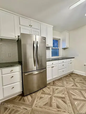 a kitchen with granite countertop a refrigerator and a stove top oven