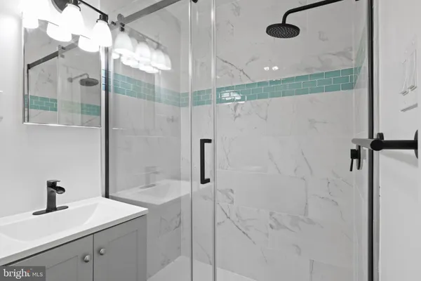 a bathroom with a sink vanity and shower