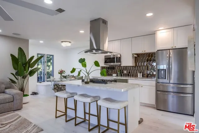 a kitchen with stainless steel appliances a dining table chairs stove and refrigerator