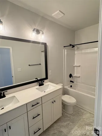 a bathroom with a double vanity sink toilet mirror and bathtub