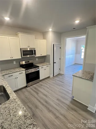a kitchen with granite countertop a stove a sink and a refrigerator