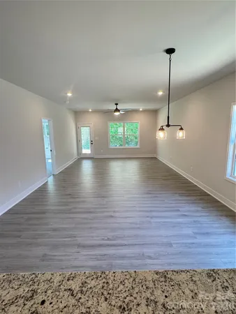 a view of an empty room with window and wooden floor