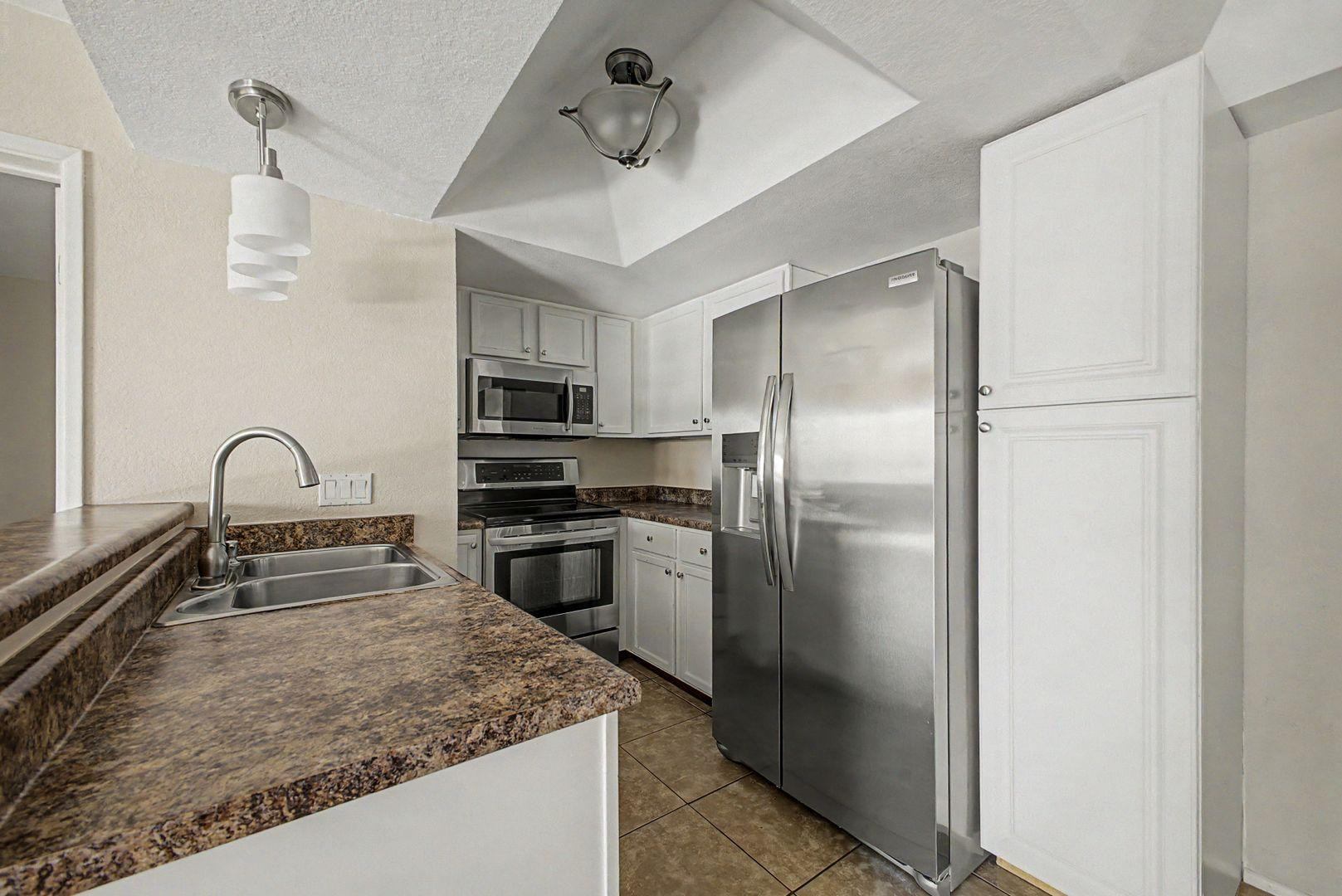 1720 East Thunderbird Road, Unit 1086 Phoenix, AZ 85022 - Photo 6 of 32 a kitchen with stainless steel appliances granite countertop a refrigerator a stove and a sink with wooden floor