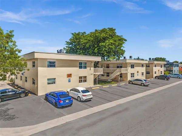 a view of a white house that has a car parked in it