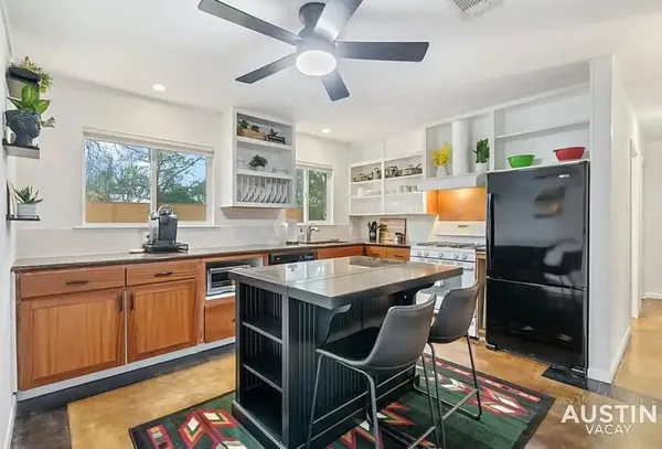 a kitchen with stainless steel appliances granite countertop a stove a refrigerator a sink a dining table and chairs with wooden floor