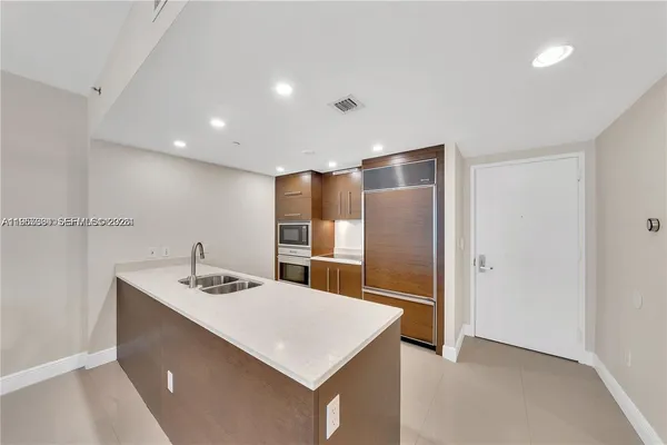 a kitchen with kitchen island a sink appliances and a refrigerator