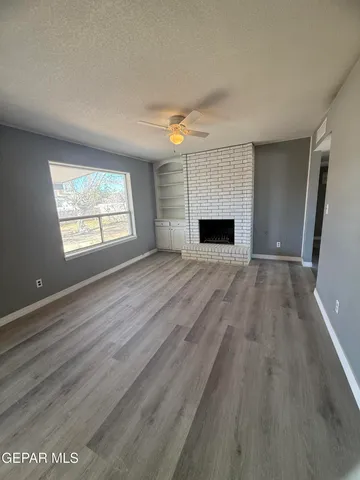 an empty room with windows fireplace and wooden floor