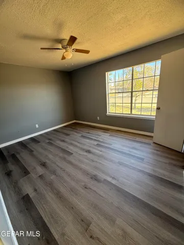 a view of empty room with wooden floor and fan