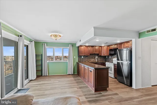 a kitchen with stainless steel appliances granite countertop a refrigerator a stove and a sink with wooden cabinets