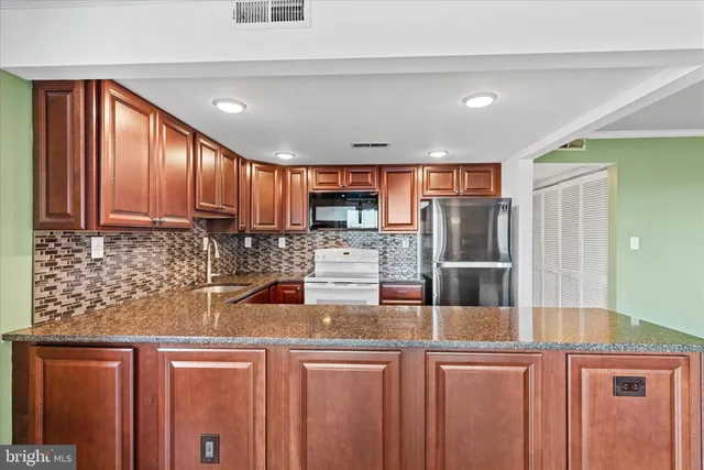 a kitchen with stainless steel appliances granite countertop a refrigerator and a stove top oven