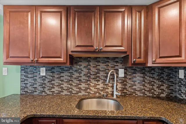 a kitchen with granite countertop wooden cabinets a sink and dishwasher