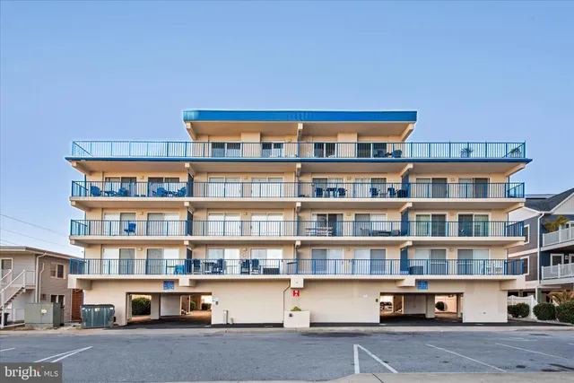 a front view of a building with lot of cars and trees