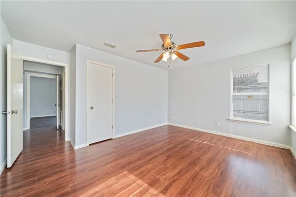 a view of empty room with wooden floor and fan