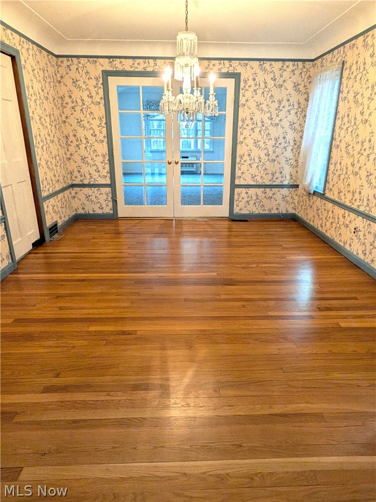 2316 Glendon Road Cleveland, OH 44118 - Photo 6 of 22 Unfurnished dining area with wood-type flooring, a chandelier, wallpapered walls, and ornamental molding