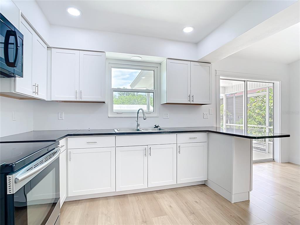 7341 Hart Street Englewood, FL 34224 - Photo 11 of 39 a kitchen with granite countertop white cabinets white appliances a sink and a window