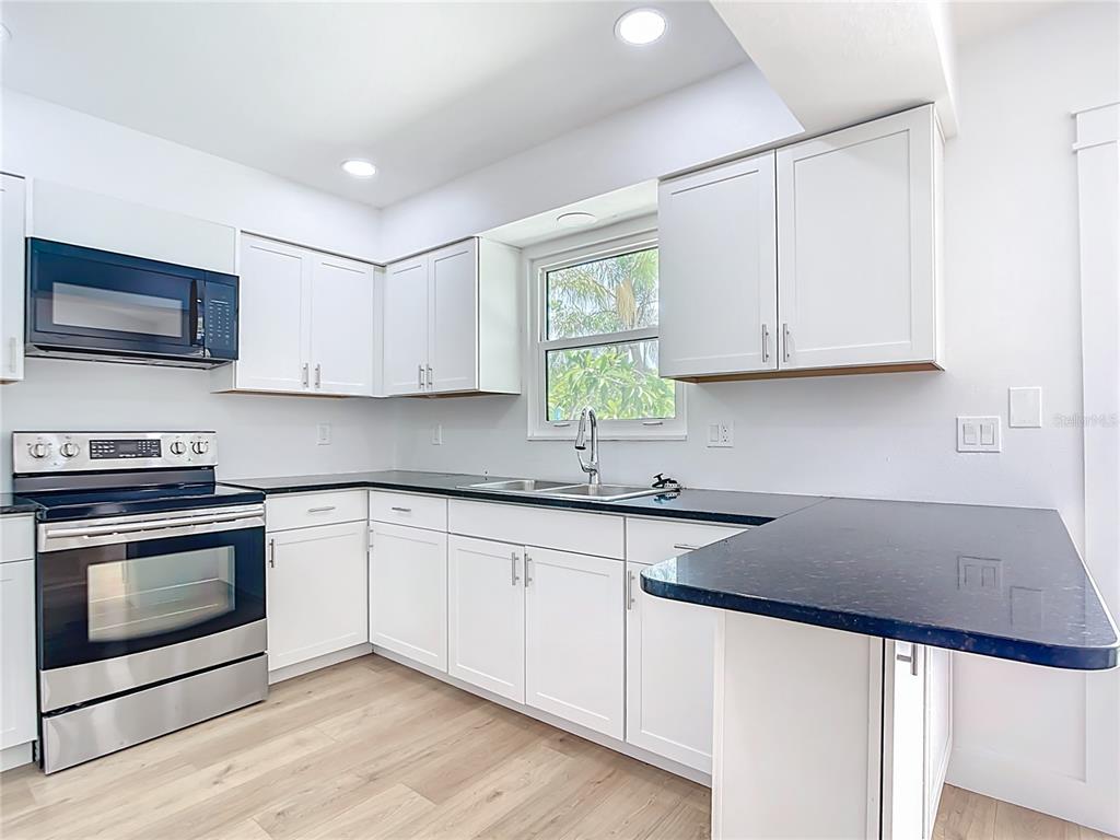 7341 Hart Street Englewood, FL 34224 - Photo 10 of 39 a kitchen with granite countertop a sink stove and microwave