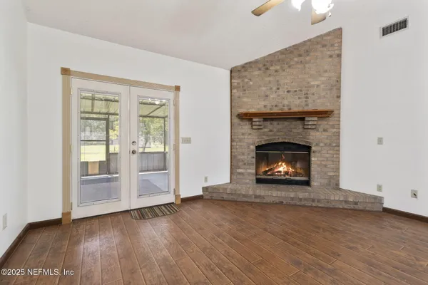 an empty room with wooden floor fireplace and windows