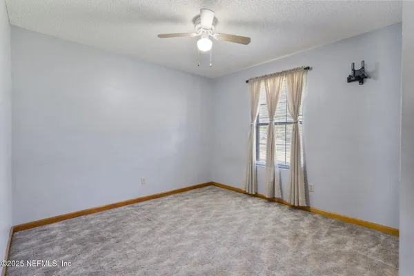an empty room with windows and fan