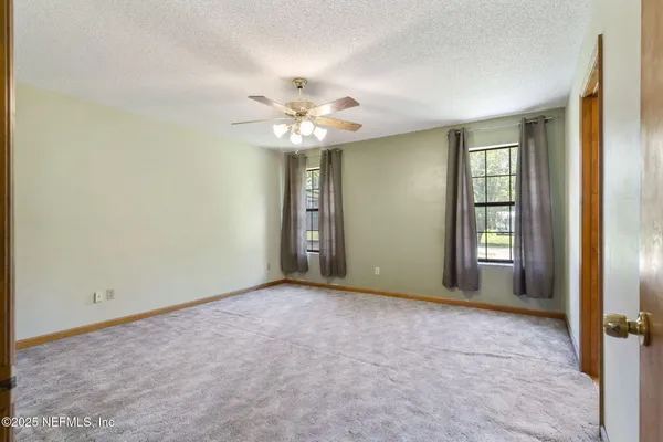 an empty room with windows and fan