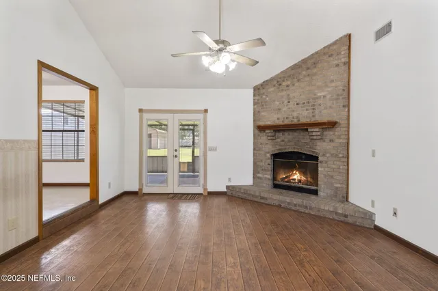 a view of an empty room with wooden floor fireplace and a window