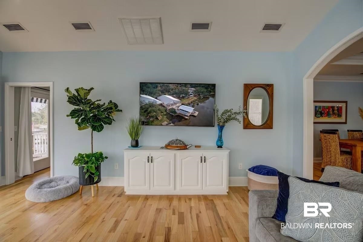 16297 Honey Road Summerdale, AL 36580 - Photo 9 of 24 Bright living space featuring light wood-finish flooring, a white built-in media console, and a large arched doorway