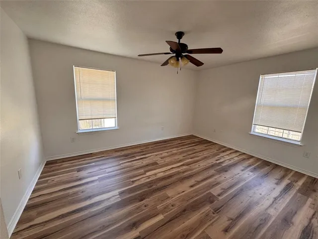 a view of empty room with wooden floor and fan
