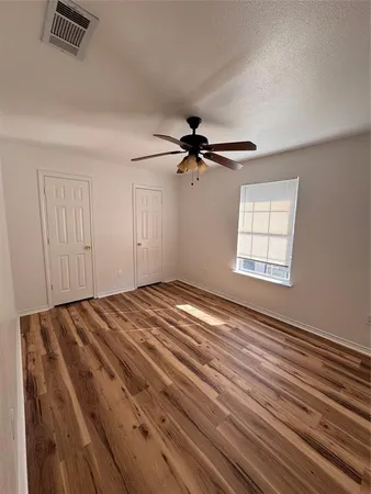 a view of empty room with wooden floor and fan