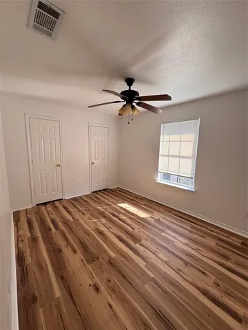 a view of empty room with wooden floor and fan
