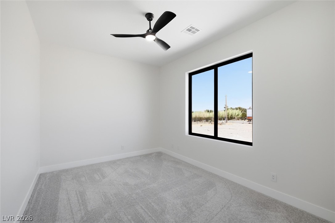 5910 East Kellogg Road Pahrump, NV 89061 - Photo 14 of 58 A well-lit bedroom with modern design, featuring a contemporary ceiling fan and a large picture window.