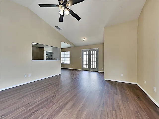 a view of a livingroom with wooden floor a ceiling fan and windows