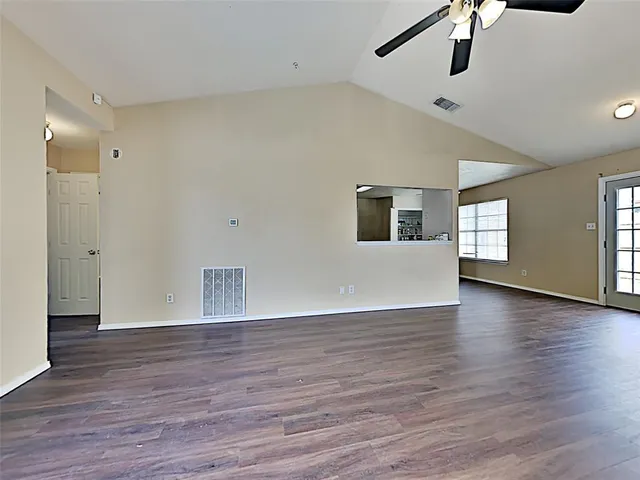 a view of an empty room with window and wooden floor