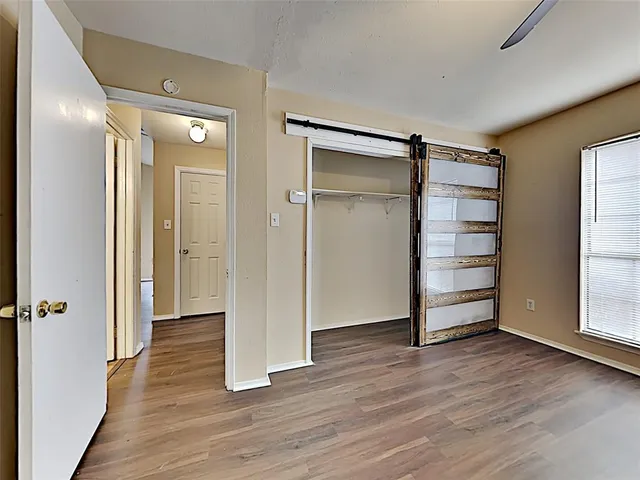 a view of an empty room with a window and wooden floor