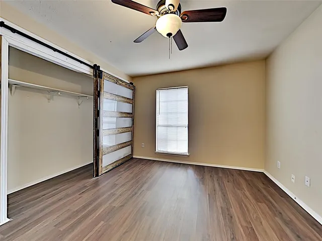 an empty room with wooden floor closet and windows