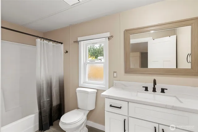 a bathroom with a sink a toilet a mirror and a window