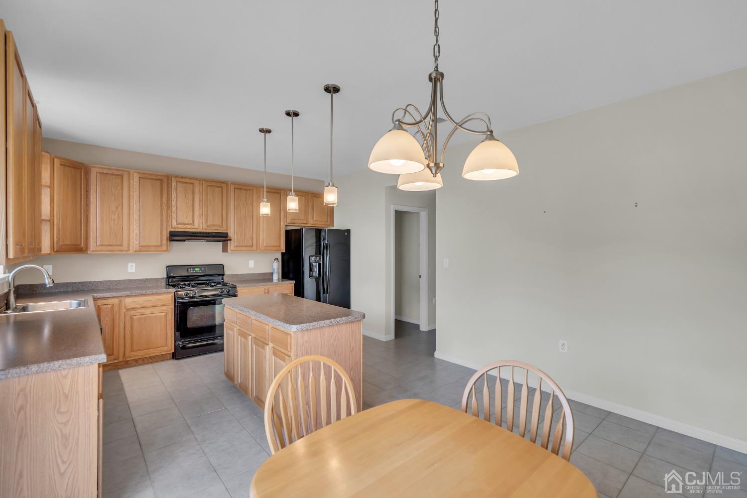 33 Carnation Road Monroe Township, NJ 08831 - Photo 20 of 46 a kitchen with stainless steel appliances granite countertop a stove a sink dishwasher a refrigerator a microwave oven with a dining table and chairs