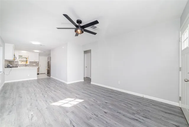 a view of empty room with wooden floor and window