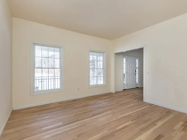 a view of an empty room with wooden floor and window