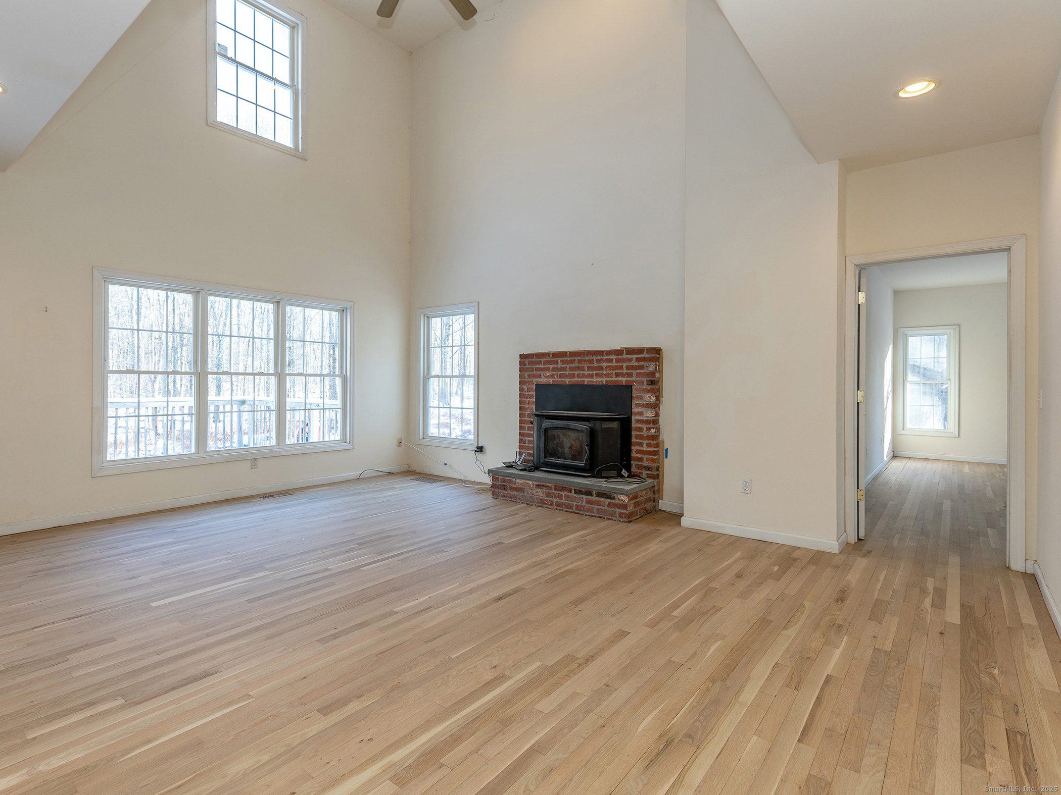 36 Sunset Lane Washington, CT 06794 - Photo 7 of 23 an empty room with wooden floor a fireplace and windows