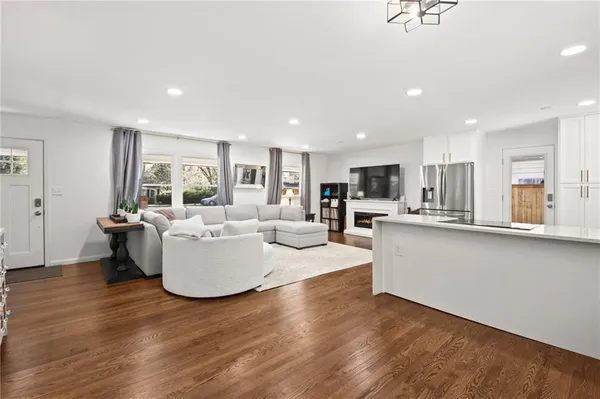 a living room with couches and kitchen view with wooden floor