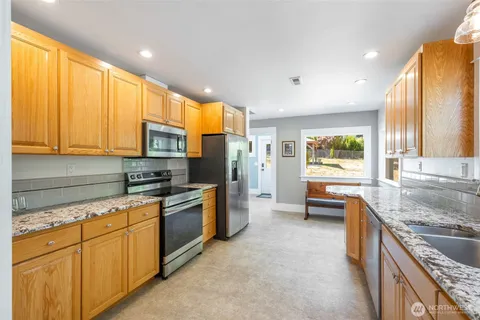 a kitchen with stainless steel appliances granite countertop a stove a sink and a refrigerator