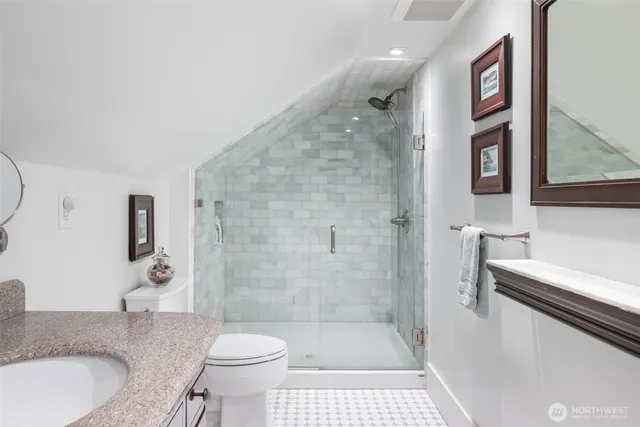 a bathroom with a granite countertop sink a toilet and shower