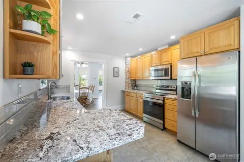 a kitchen with stainless steel appliances granite countertop a refrigerator a stove and a sink with wooden floor